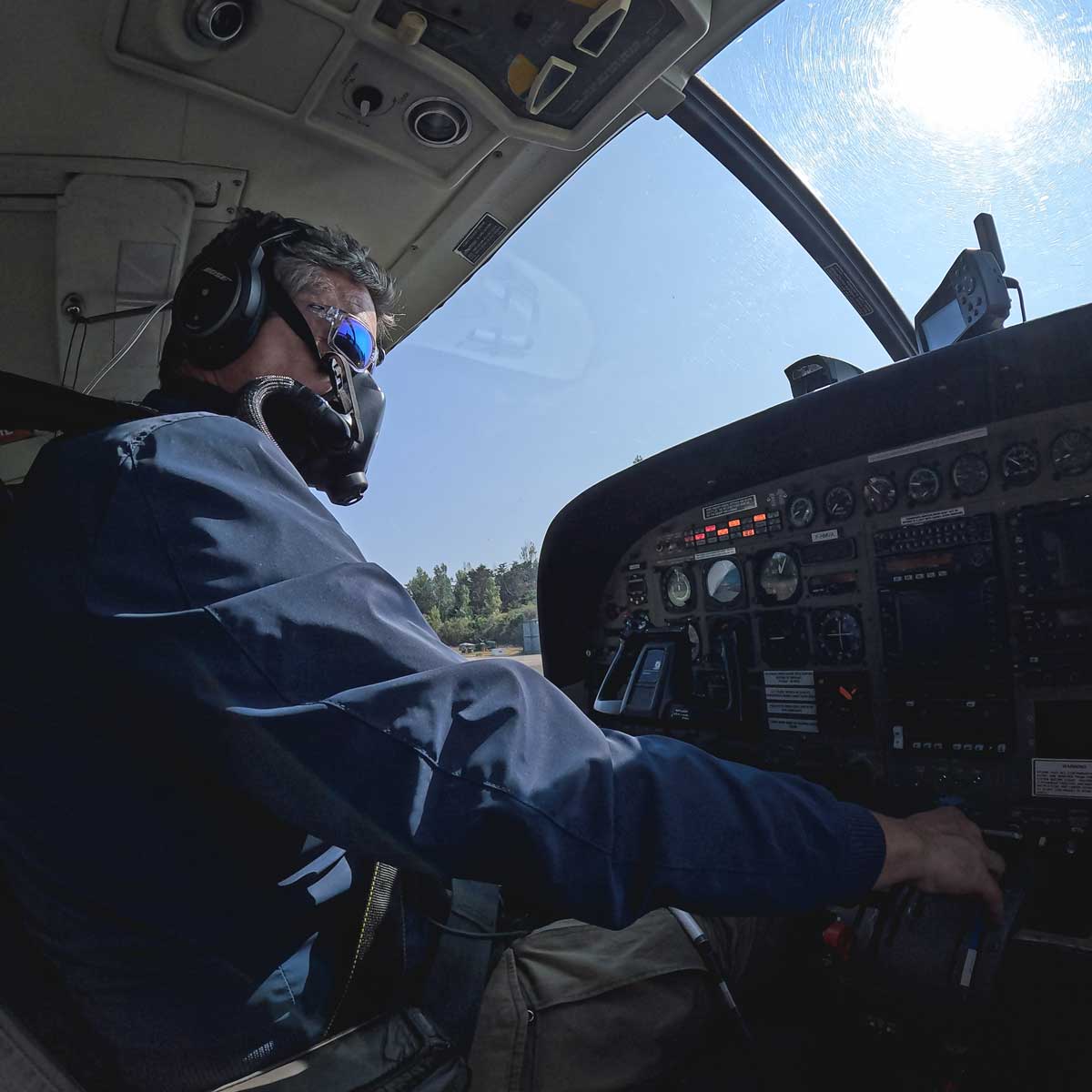 Pilote Vendée Aviation aux commandes du Cessna de Vendée Évasion sur l'aérodrome de la Lande aux Sables-d'Olonne — casque audio, lunettes miroir, tableau de bord instruments visibles, piste et végétation en arrière-plan